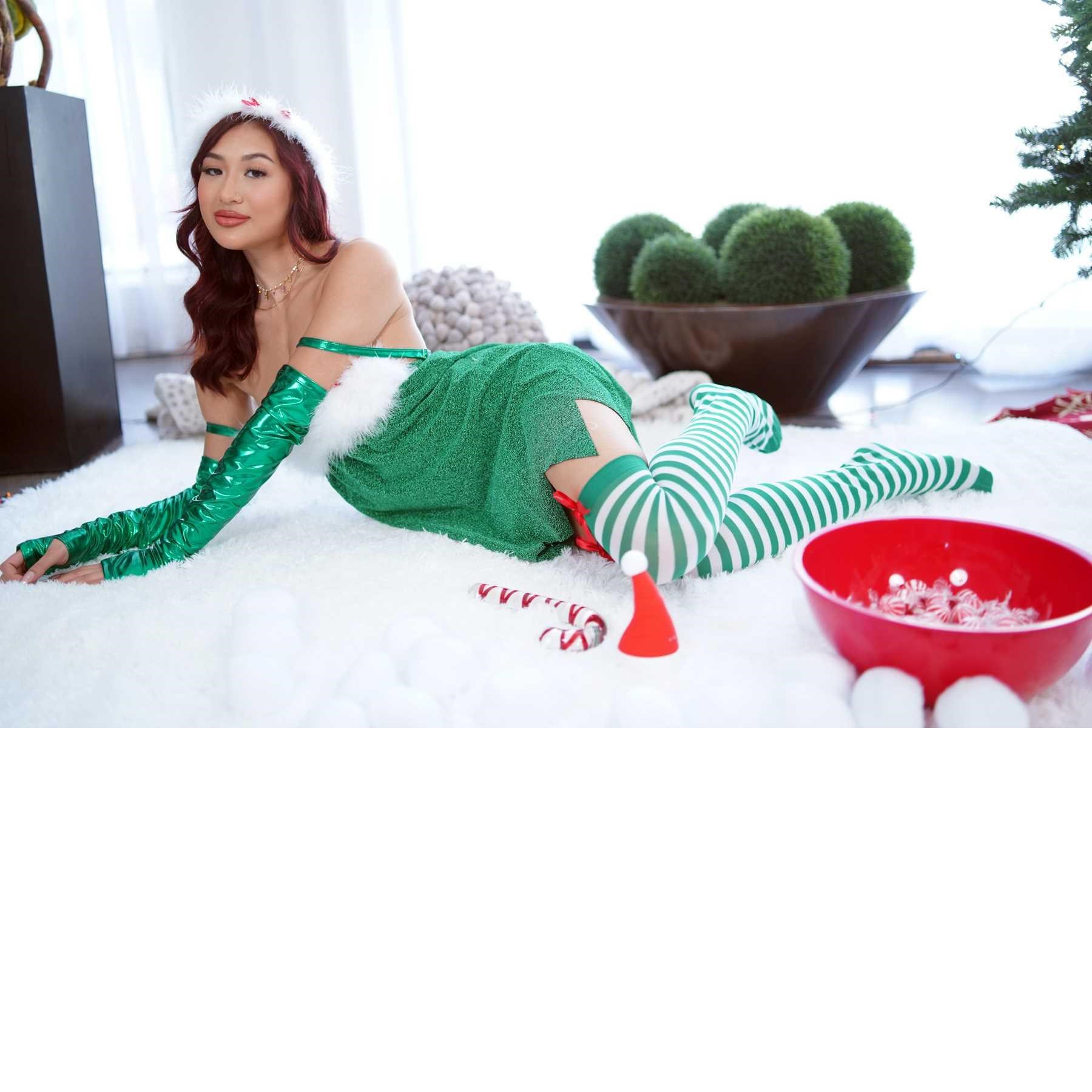 Brunette female posed lounging wearing Christmas elf attire