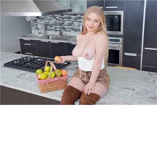 Blonde female posed topless on kitchen counter displaying breasts