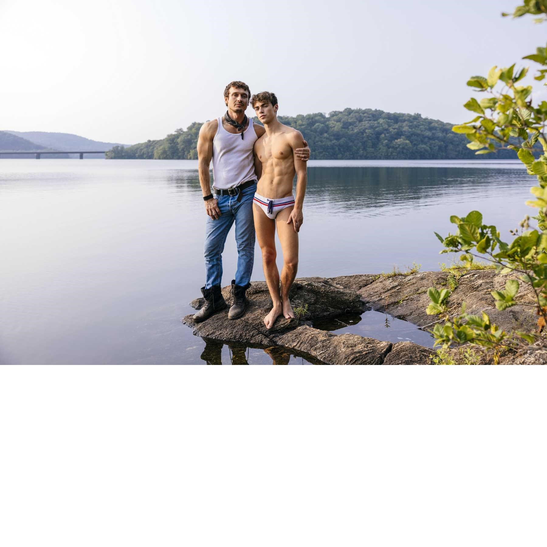 Male wearing briefs caressing clothed male outdoors