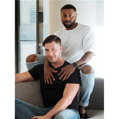 Two clothed males posed on couch